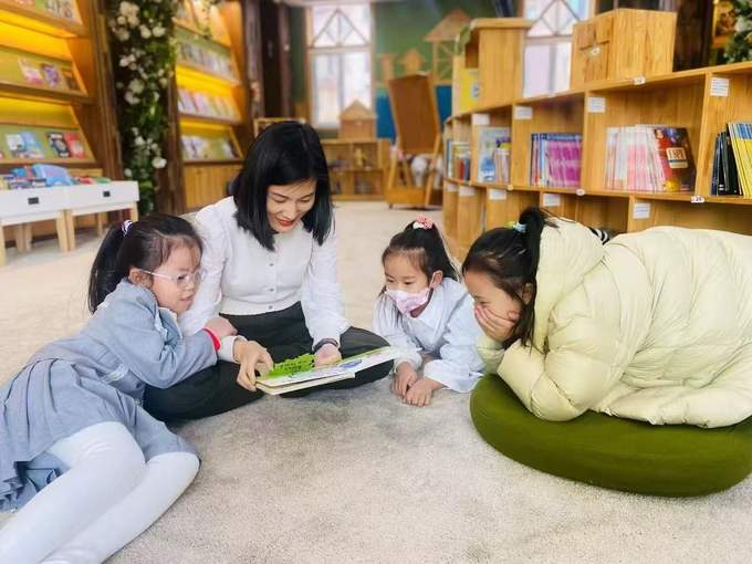中教老师和三个孩子趴在地毯上读绘本